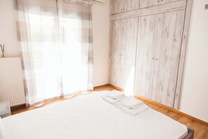 A bedroom with a large bed, a wooden wardrobe, and sheer curtains. - Cozy apt near Stavros Niarchos Park (Kallithea)