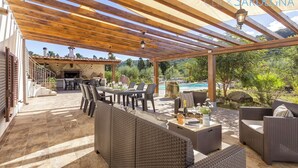 Eine Terrassenausstattung im Freien mit Korbmöbeln, einem Pool und einem Kamin aus Stein.