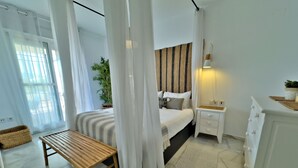 A bedroom with a bed, bedside table, nightstand, and a small wooden bench.