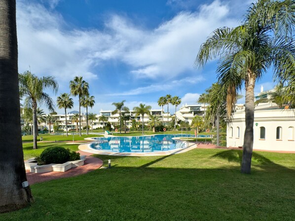 A pool area with palm trees and a clear blue sky.