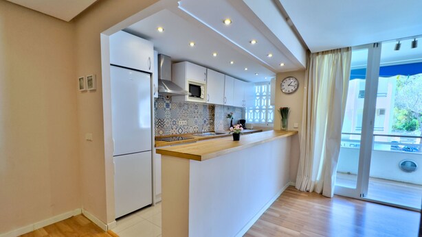 A modern kitchen with white appliances, a wooden countertop, and a decorative backsplash. - Cozy holiday apt Marbella center. (Marbella)