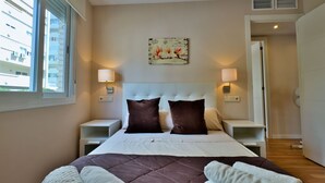 A hotel room with a large bed, two bedside tables, a headboard, and a window with blinds. - Cozy holiday apt Marbella center. (Marbella)