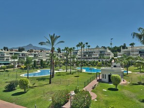 A resort with multiple swimming pools, palm trees, and a mountainous backdrop.
