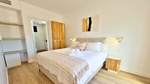 A modern bedroom with a large bed, wooden headboard, bedside tables, and a wardrobe. - Spacious Apartment with Terrace near Beach Puerto Banus (Marbella)