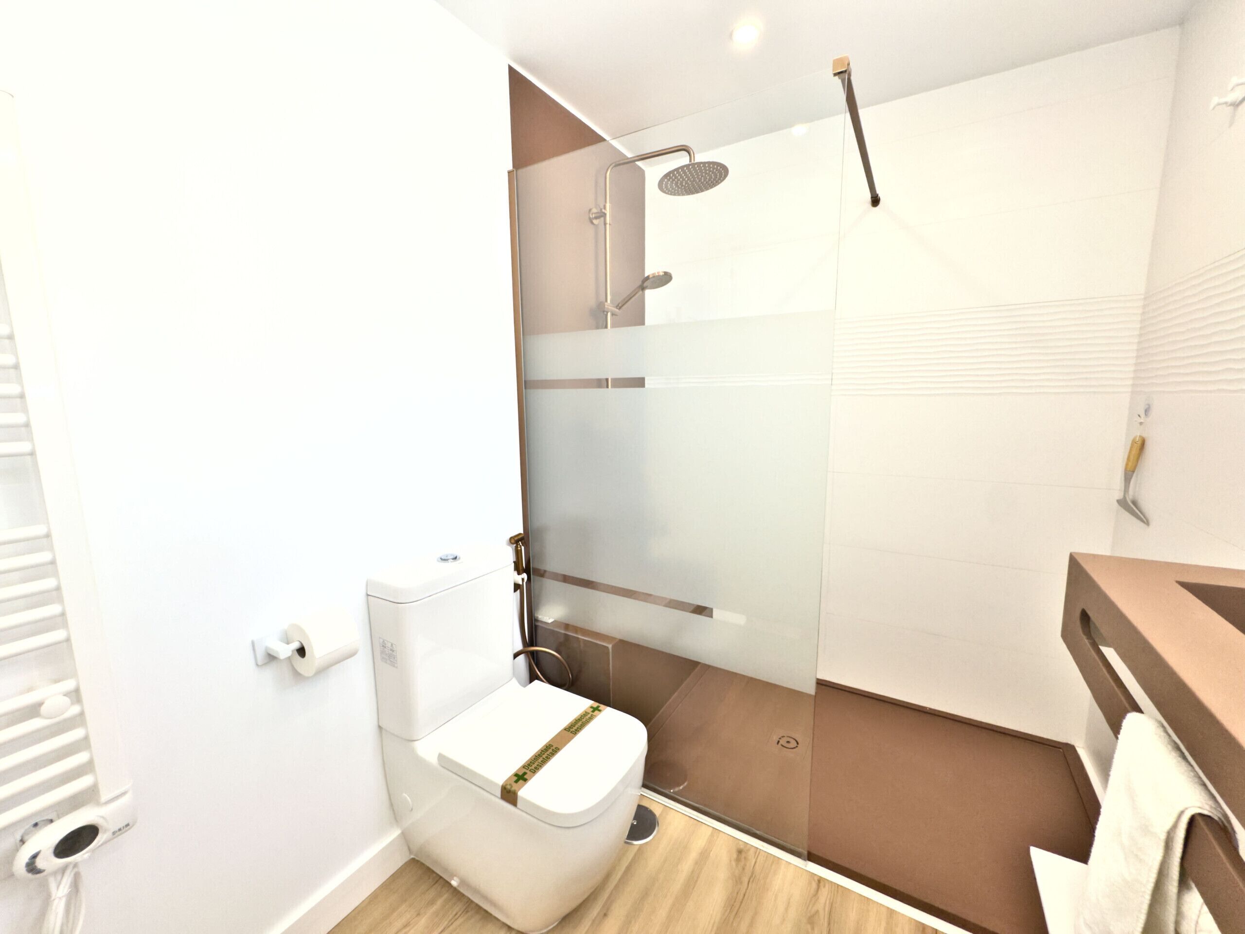 A modern bathroom with a glass-enclosed shower, a toilet, and a wooden vanity.