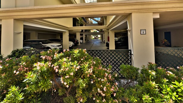 A multi-level parking structure with a covered walkway, surrounded by greenery and a decorative fence. - Spacious Apartment with Terrace near Beach Puerto Banus (Marbella)