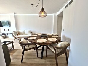 A dining area with a round wooden table, woven placemats, and wicker chairs.