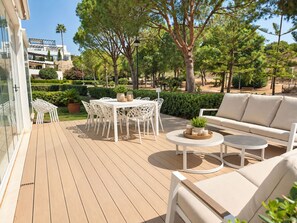 An outdoor patio with a white table and chairs, a round table with candles, and a sofa. - Luxury Townhouse Santa Clara Golf (Marbella)