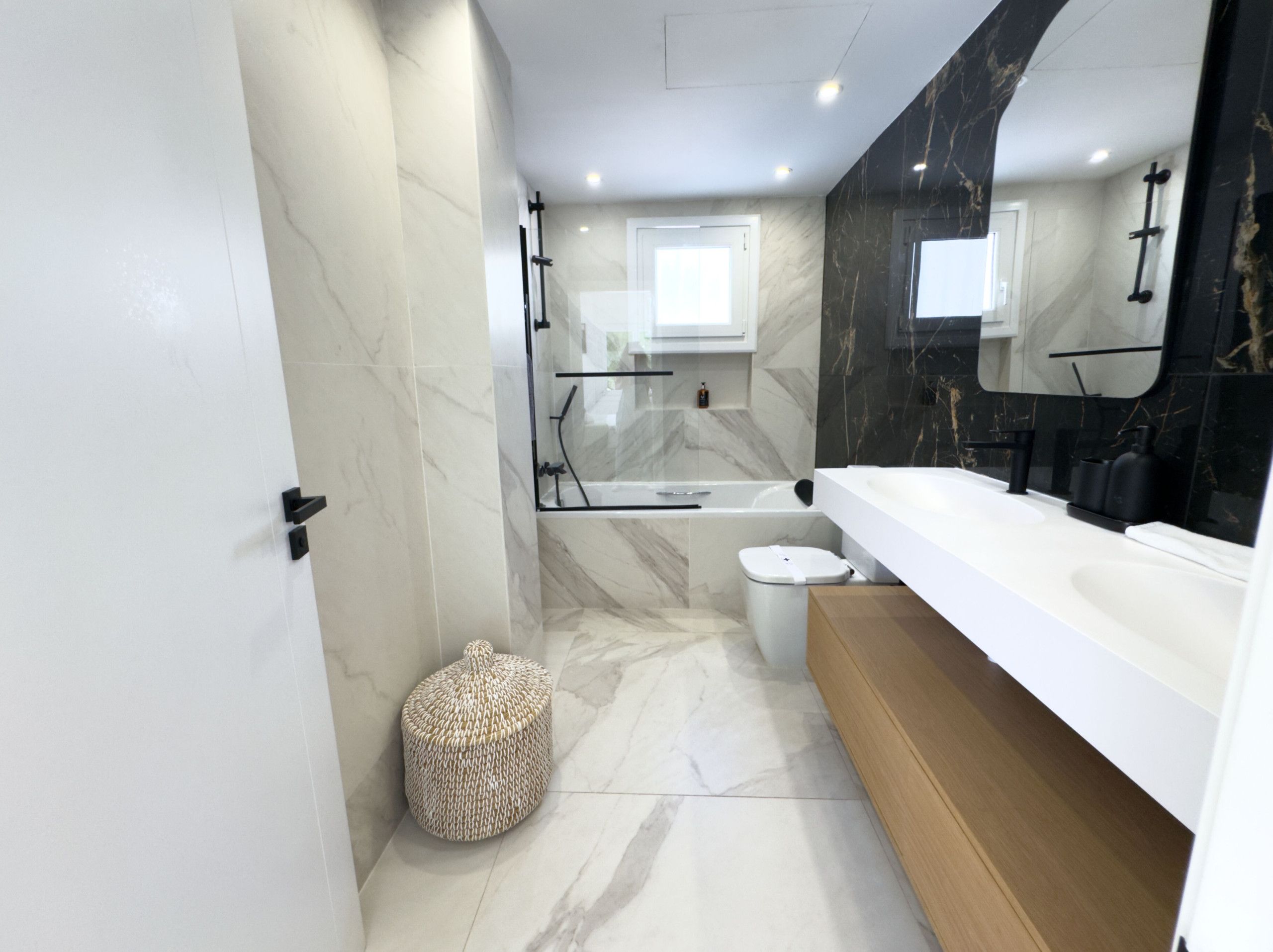 A modern bathroom with a bathtub, toilet, and vanity.