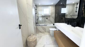 A modern bathroom with a bathtub, toilet, and vanity.