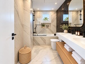A modern bathroom with a bathtub, toilet, and vanity. - Luxury Townhouse Santa Clara Golf (Marbella)
