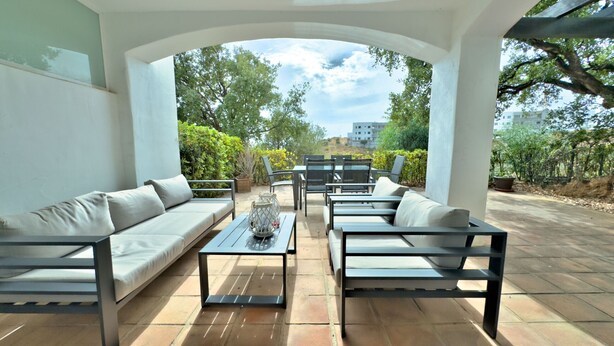 Une terrasse extérieure aménagée avec un ensemble de canapés, une table basse et un coin repas.