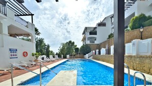 Une piscine équipée de chaises longues et d’une bouée de sauvetage fixée au mur.