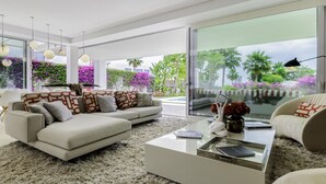 Una sala de estar moderna con un juego de sofá, una mesita de centro y vista a un jardín con plantas tropicales.