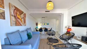 Una sala moderna con un sofá, sillones, un televisor y obras de arte en las paredes.