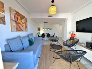 A modern living room with a sofa, chairs, a TV, and artwork on the walls.
