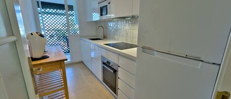 A modern kitchen with white cabinets, a stainless steel sink, and a digital inverter refrigerator.