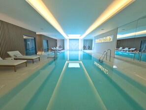 Una piscina interna moderna con aree relax, vista chiara sulla vasca e un cartello con la scritta "Soul Marbella".