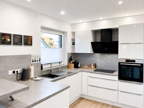 Une cuisine moderne avec des meubles blancs, une hotte noire et un four encastré.