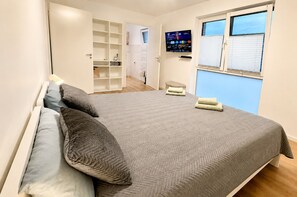A bedroom with a bed, pillows, a TV, a window, and a wardrobe. - To complete (Kaarst)
