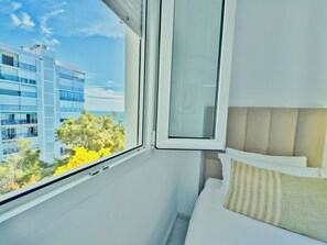 A hotel room with a bed, a window, and a view of a building and trees.