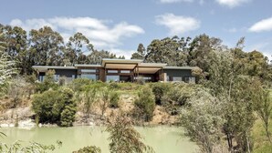 Une maison moderne à deux étages, dotée d’un toit plat, de grandes fenêtres et d’un patio couvert.