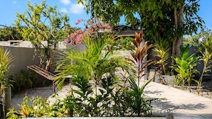 A table with a cup and saucer, surrounded by greenery and a tree. - Bon Abri maldives (Magoodhoo)