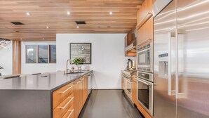 A modern kitchen with wooden cabinets, stainless steel appliances, and a large island. - Cedar Loft Villa (Venice)