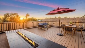 A deck with a fire feature, outdoor seating, and a view of the sunset. - Cedar Loft Villa (Venice)