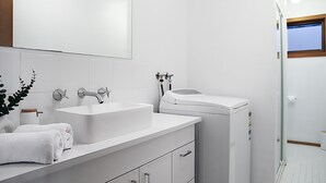 A modern bathroom with a white sink, vanity, and a glass shower enclosure.