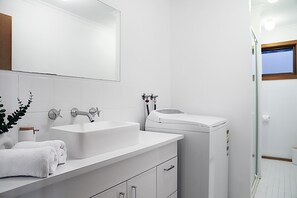 A modern bathroom with a white sink, vanity, and a glass shower enclosure.