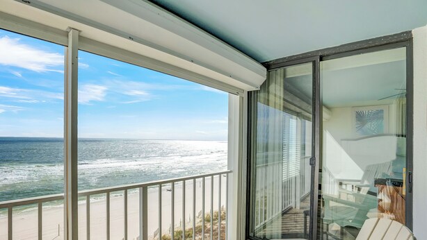 A balcony with a view of the ocean, a glass door, and a chair. - Summerchase 704 by Liquid Life (Orange Beach)