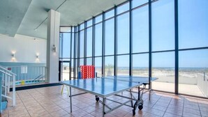A ping pong table in a spacious room with large windows and a view of the city. - Summerchase 704 by Liquid Life (Orange Beach)