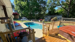 Une terrasse en bois avec une piscine, un jacuzzi et un espace salon abrité.
