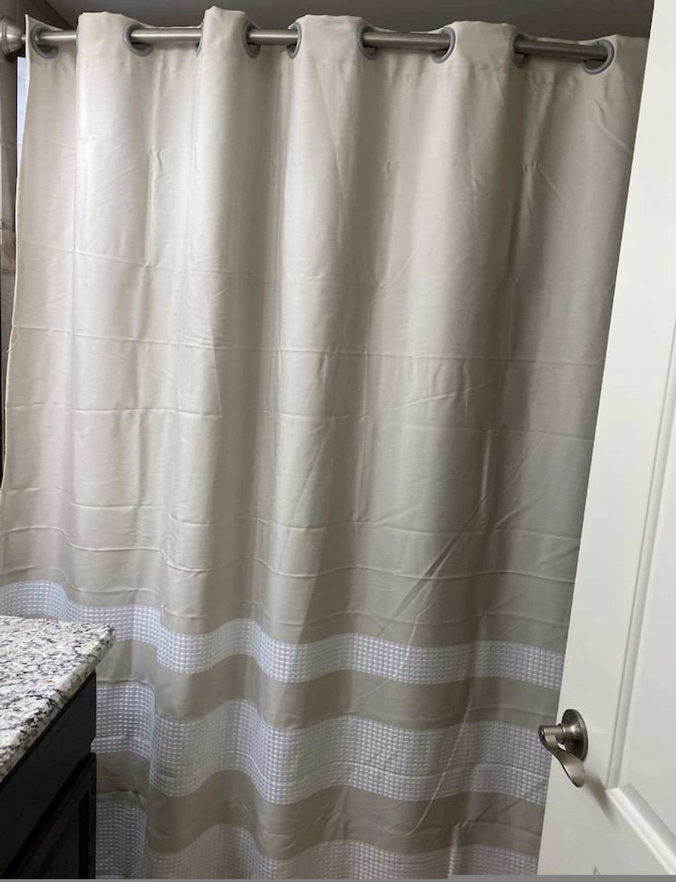A bathroom with a white shower curtain and a marble countertop.