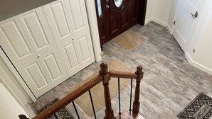 Un escalier en bois, doté d’une rampe métallique, mène à une porte avec un panneau de verre.
