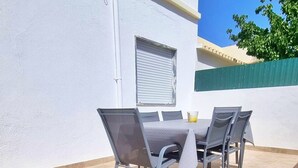 An outdoor patio with a table and chairs, a window, and a white wall. - Cozy Townhouse, quiet location, near the river and outdoor space (Estômbar)
