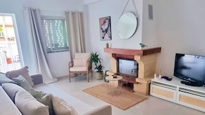 A living room with a sofa, a fireplace, a television, and a hanging light fixture. - Cozy Townhouse, quiet location, near the river and outdoor space (Estômbar)