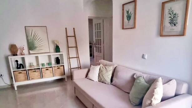 A spacious living room with a white sofa, a wooden sideboard, and a woven rug. - Cozy Townhouse, quiet location, near the river and outdoor space (Estômbar)