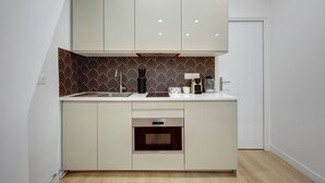 A compact kitchen with a built-in oven, a coffee maker, and a microwave. - Charming 1BR in Montorgueil - Les Halles (Paris)