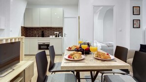 A modern kitchen with white cabinets, a microwave, and a dining area with a table set for breakfast. - Charming 1BR in Montorgueil - Les Halles (Paris)