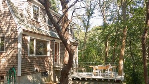 A wooden house with a deck, surrounded by trees. - Quiet, cozy home in the woods CS0038 (Wellfleet)