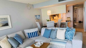 A living room with a grey sofa, a wooden coffee table, and a patterned rug. - Ocean Front Condo in New Smyrna Beach FL (New Smyrna Beach)