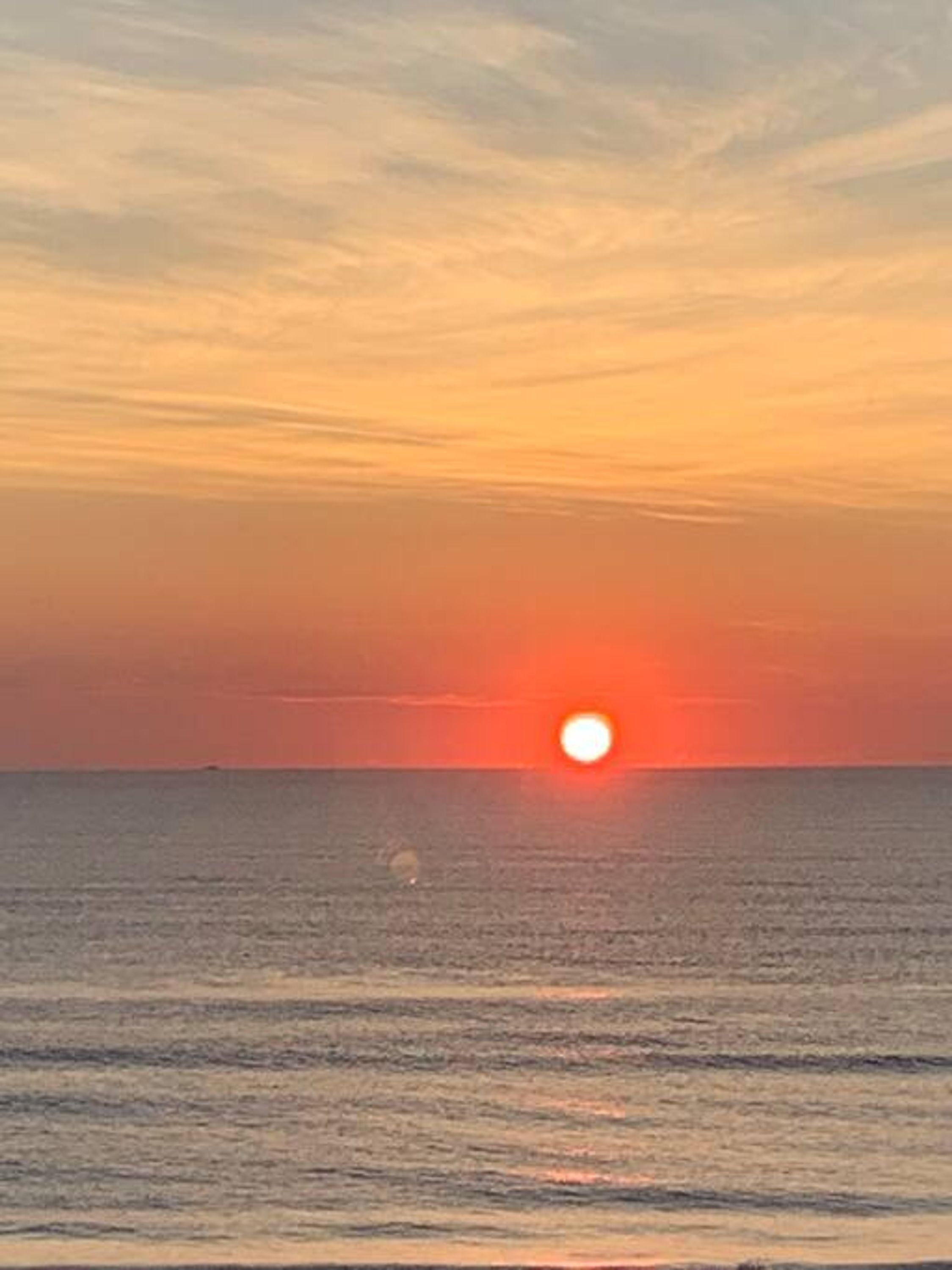 A sunset over a calm sea with a clear horizon.