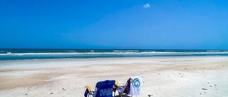 A beach with two beach chairs and a towel.