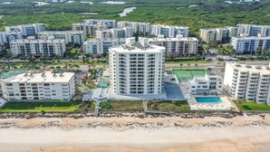 A coastal residential area with modern apartment buildings, a beach, and a large body of water in the background. - Oceanview 3 Bedroom Condo New Smyrna Beach FL (New Smyrna Beach)
