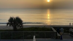 A sunset view from a pier with a palm tree and a person walking. - Oceanview 3 Bedroom Condo New Smyrna Beach FL (New Smyrna Beach)
