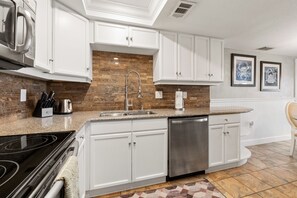Una cocina moderna con armarios blancos, lavavajillas de acero inoxidable y encimera de granito.