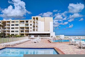 Un hotel con zona de piscina, varios balcones y vista al océano.