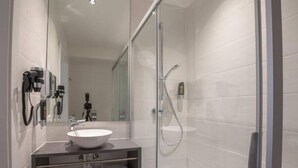 A modern bathroom with a glass shower enclosure, a white sink, and a mirror. - Double Room - Disability access by Arbio (Vienna)